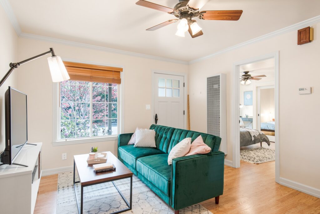 living room with a green couch and fan on the ceiling